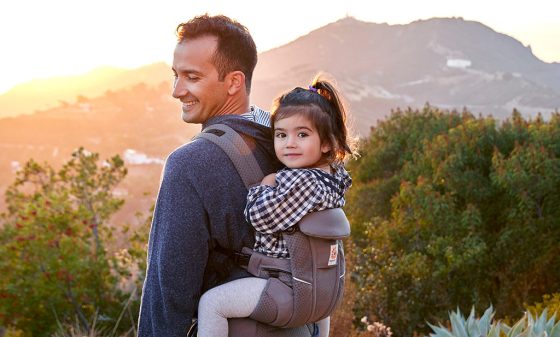 Dad carries toddler in a Ergobaby Baby carrier