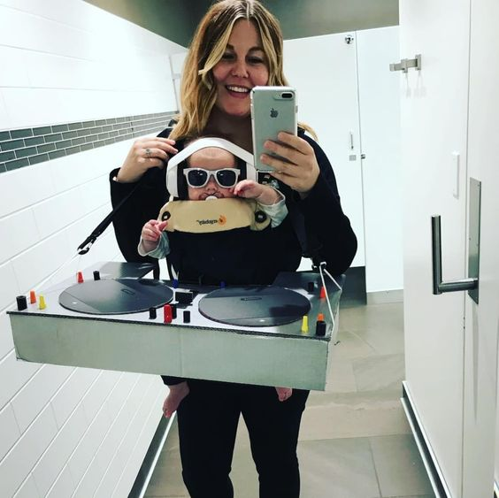 mom holding baby in Ergobaby carrier dressed up as baby DJ