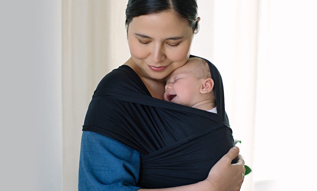 baby sleeping and smiling in a baby wrap